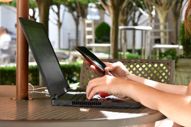 A woman on computer working outside and connecting to a free wifi hotspot.